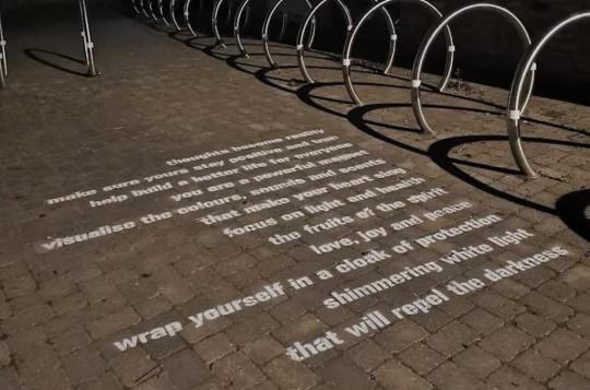 Short poem stencilled onto city street in white letters
