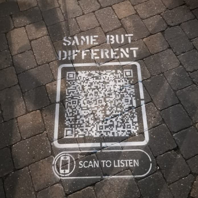 QR Code stencilled onto pavement with instruction: scan to listen