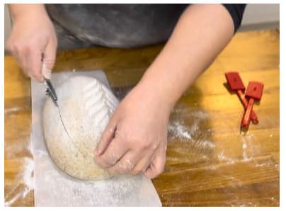 Cutting the bread to allow the dough to rise without distorting the design