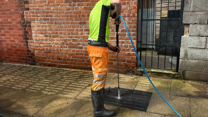 Applying clean graffiti stencils with pressure washer for Liverpool Football Club